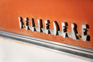 Picture of a 1957 Plymouth Belvedere Emblem, chrome on well preserved orange and white paint